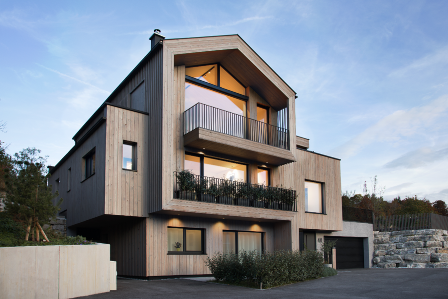 Mehrstöckige Villa mit Satteldach, Holzfassade, angebauter Garage und Doppelbalkon von Josko.