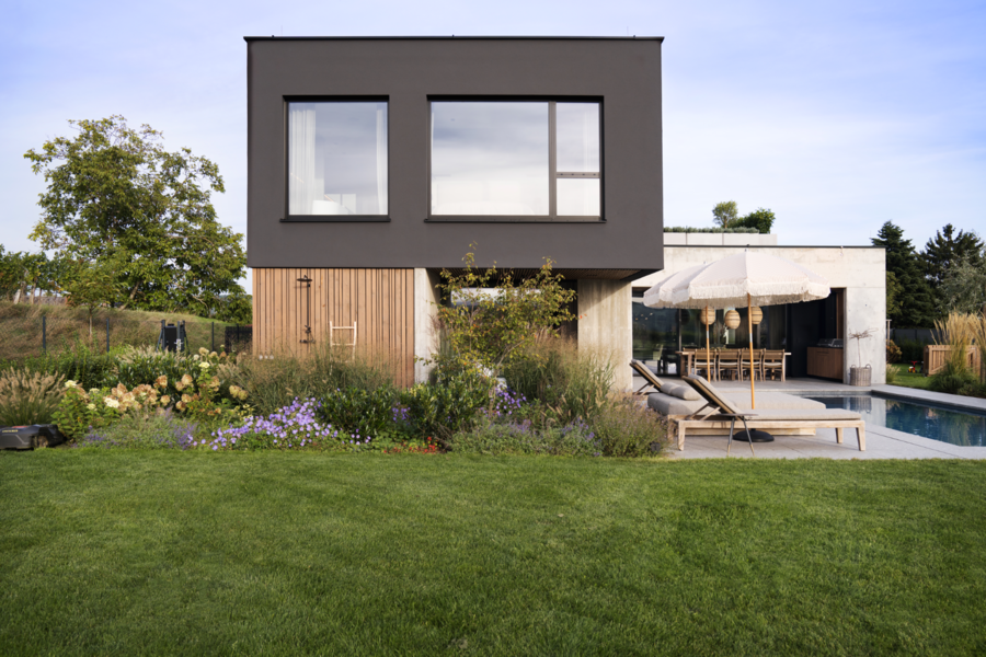 Aussenansicht eines modernen Flachdachhauses mit einer Mischung aus Holzfassade und Betonbau, einem Garten, Pool und bodentiefen Fenstern von Josko.