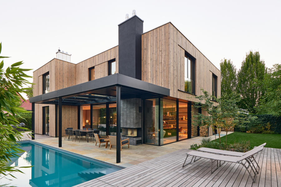 Einfamilienhaus mit Flachdach, Holzfassade, überdachtem Terrassenbereich, Pool, Garten, Hebeschiebetüren und Ganzglassystem von Josko.