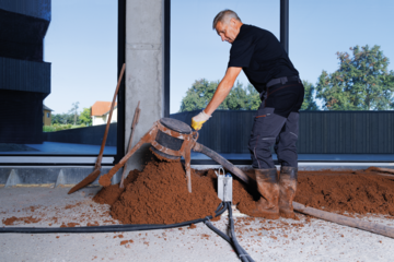 Arbeiter beim Fußbodenaufbau mit thermotec® in einem Raum mit bodentiefen Fenstern von thermotec®.