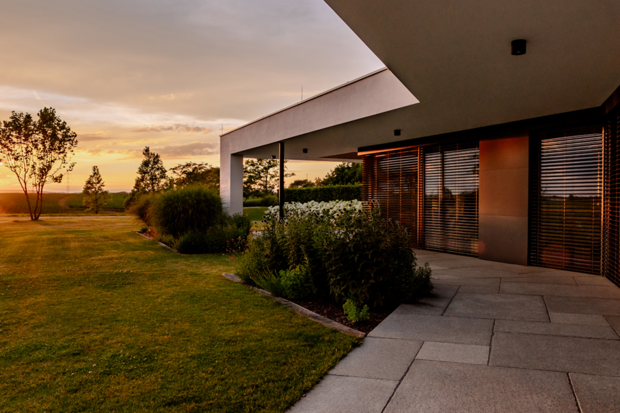 Newo Sonnen- und Insektenschutz zeigt ein modernes Einfamilienhaus mit großen Glasfronten auf denen Rollläden als Sonnenschutz angebracht wurden.