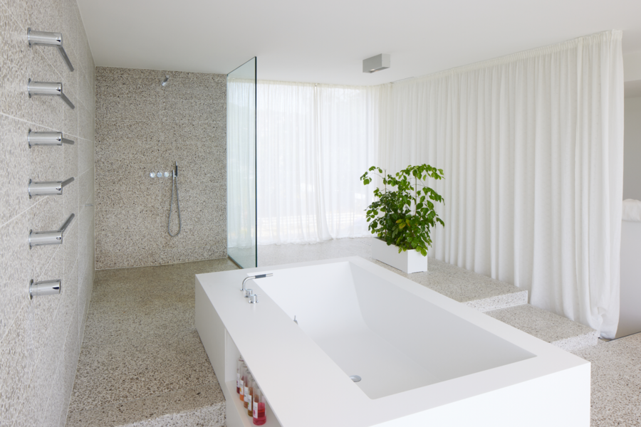 Badezimmer mit Badewanne und offener Dusche, Fliesen in Terrazzooptik und Armaturen und Handtuchwärmer in Silber von Vola.