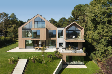 Mehrstöckiges Doppelhaus mit Holzfassade, Balkon, Terrasse und großem Garten von Weissenseer Holz-System-Bau.