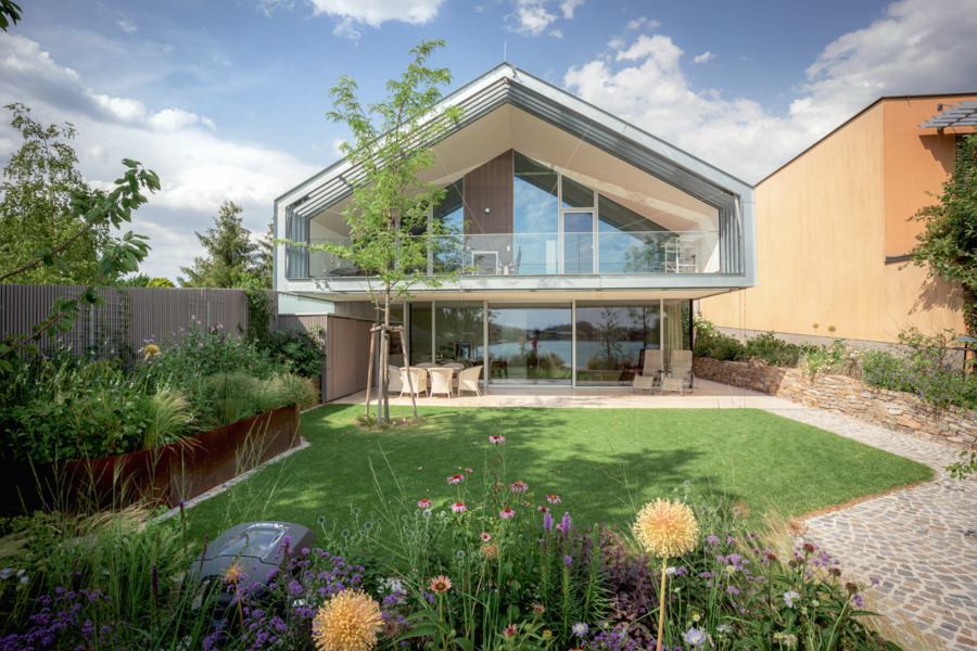 Villa mit Satteldach, überdachtem Balkon, Terrasse und Garten von Weissenseer Holz-System-Bau.