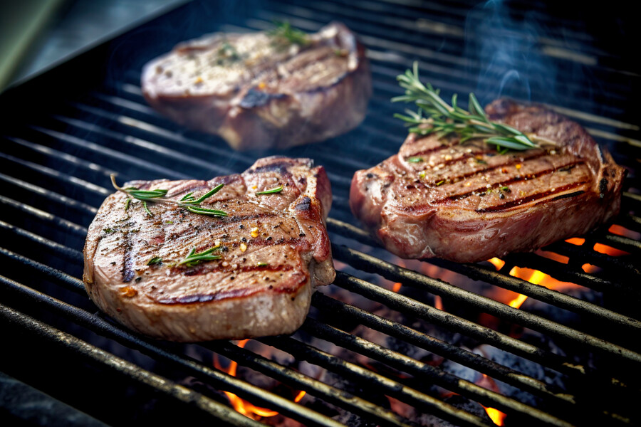 Dampfendes Grillfleisch auf heißem Grillrost.