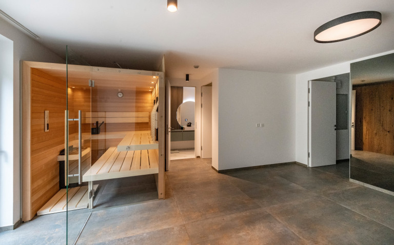 Grosse hauseigene Sauna mit grossformatigem Fliesenboden mit Blick ins moderne Badezimmer von AL Architekt.