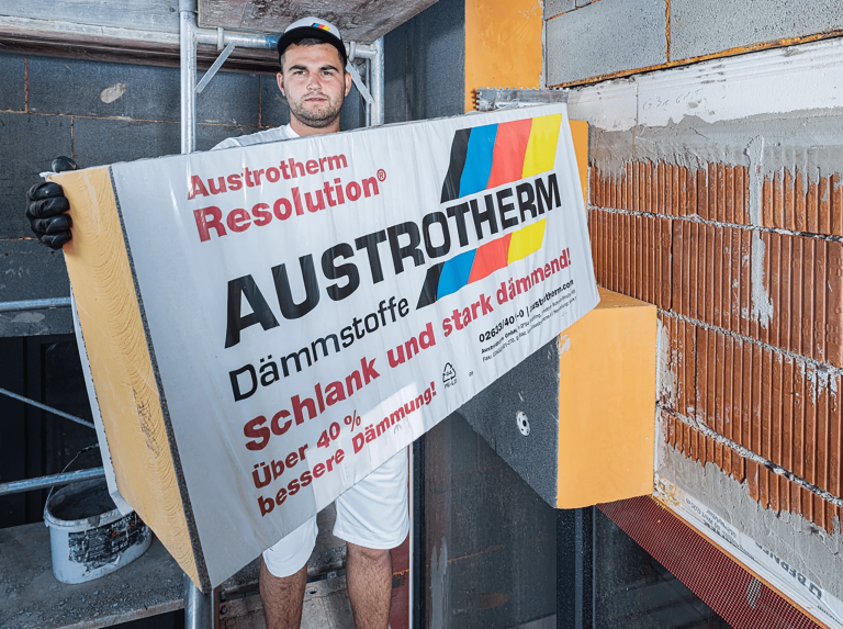 Bauarbeiter mit Dämmmaterial von Austrotherm auf einer Baustelle.