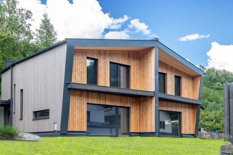 Modernes Wohnhaus mit Satteldach, Balkon, Holzfassade, große ebenerdige Fensterflächen von Erler Haus.