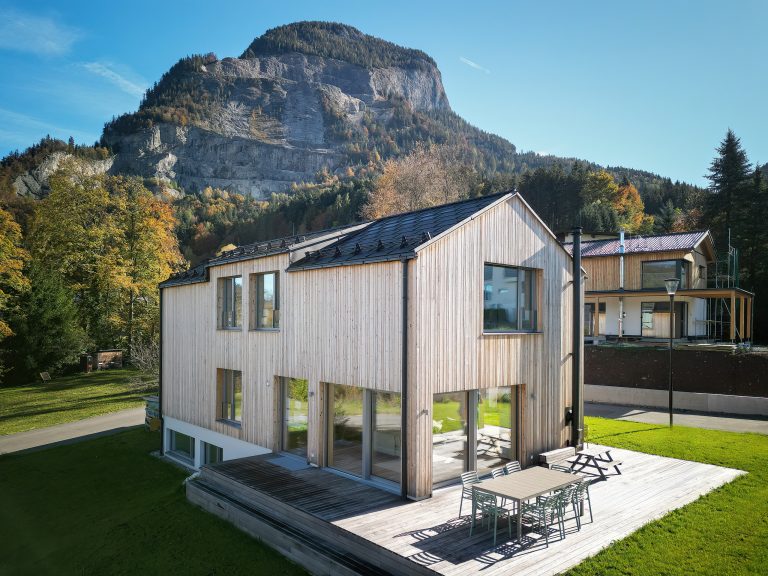 Erler Haus zeigt Einfamilienhaus mit Holzfassade, Holzterrasse mit Stufen in den Garten.