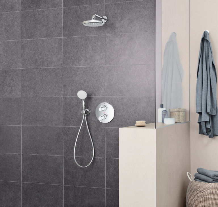 Duschnische mit Überkopf-Dusche und Hand-Dusche mit silber Chrom-Armaturen von Grohe mit dunklen Wandfliesen.