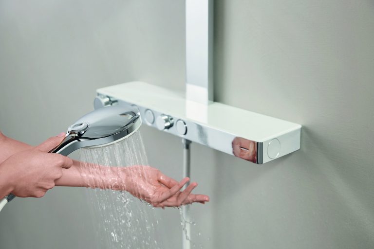 Wandmontierte Armatur in Chrome mit Temperaturregler Handbrause und weissem Brauseschlauch von GROHE.