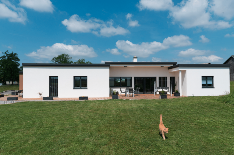 HARTL HAUS Holzindustrie zeigt einen modernen Bungalow in Fertighausbauweise mit Flachdach und Terrasse.