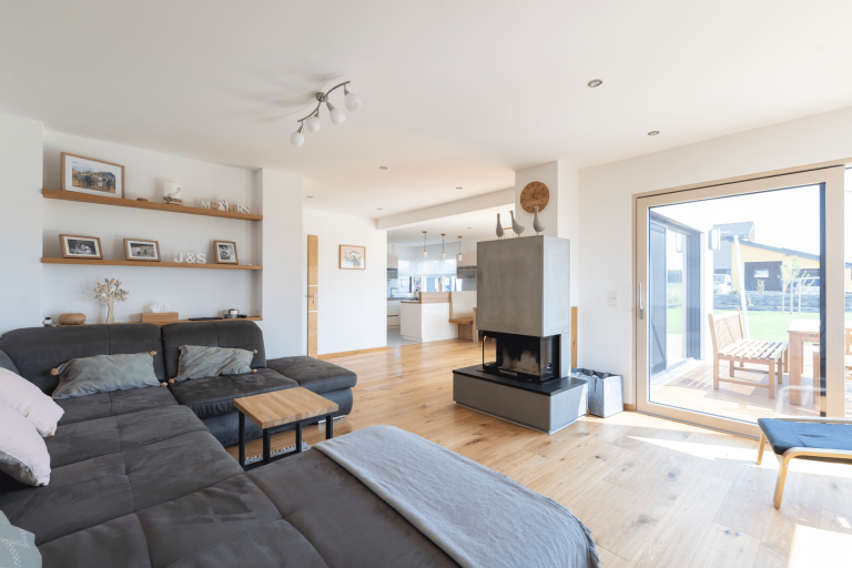 Hartl Haus zeigt eine Wohnwand aus Holz mit weißen Laden, einem Fernseher und Holzdekoration.