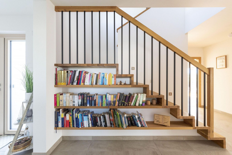 Hartl Haus zeigt platzsparenden Stiegenaufgang mit integrierten Regalen unter den Treppen.