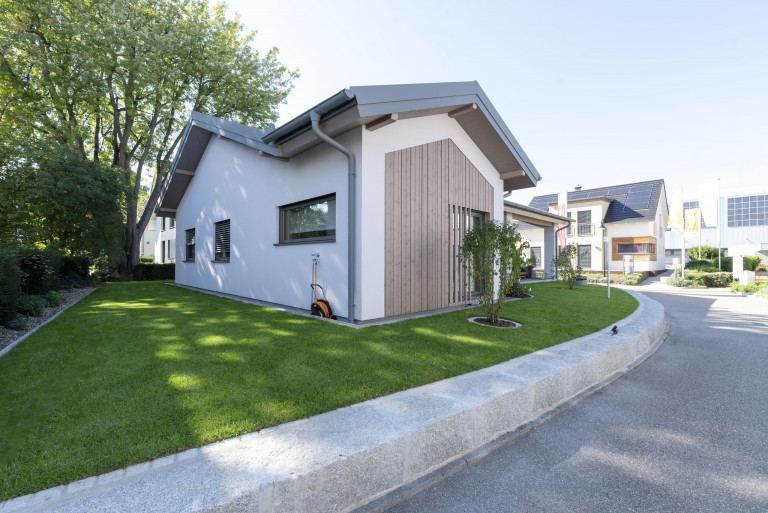 Bungalow mit Satteldach, Holzverkleidung an einer Fassadenseite, überdachtem Parkplatz von Hartl Haus.