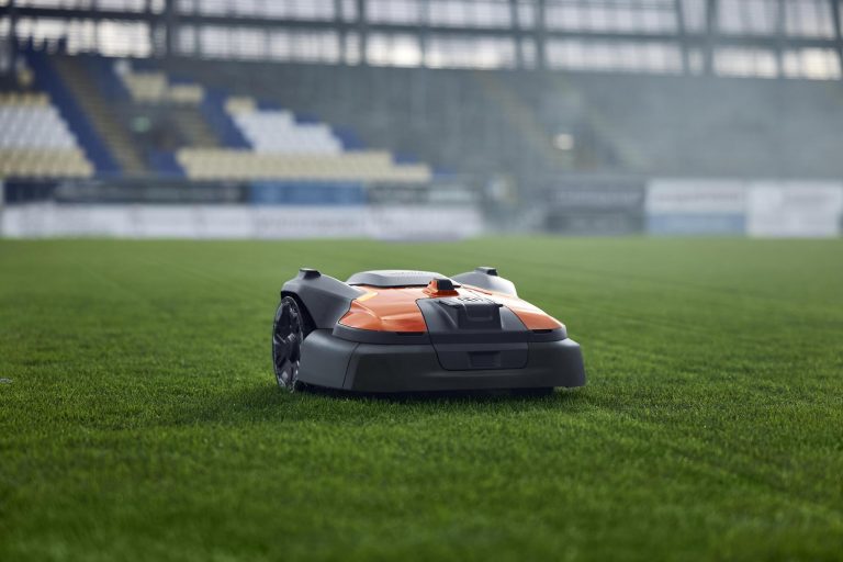 Der Husqvarna Automower 560 EPOS Sports mäht den Rasen eines Fussballfeldes in einem großen Stadion.