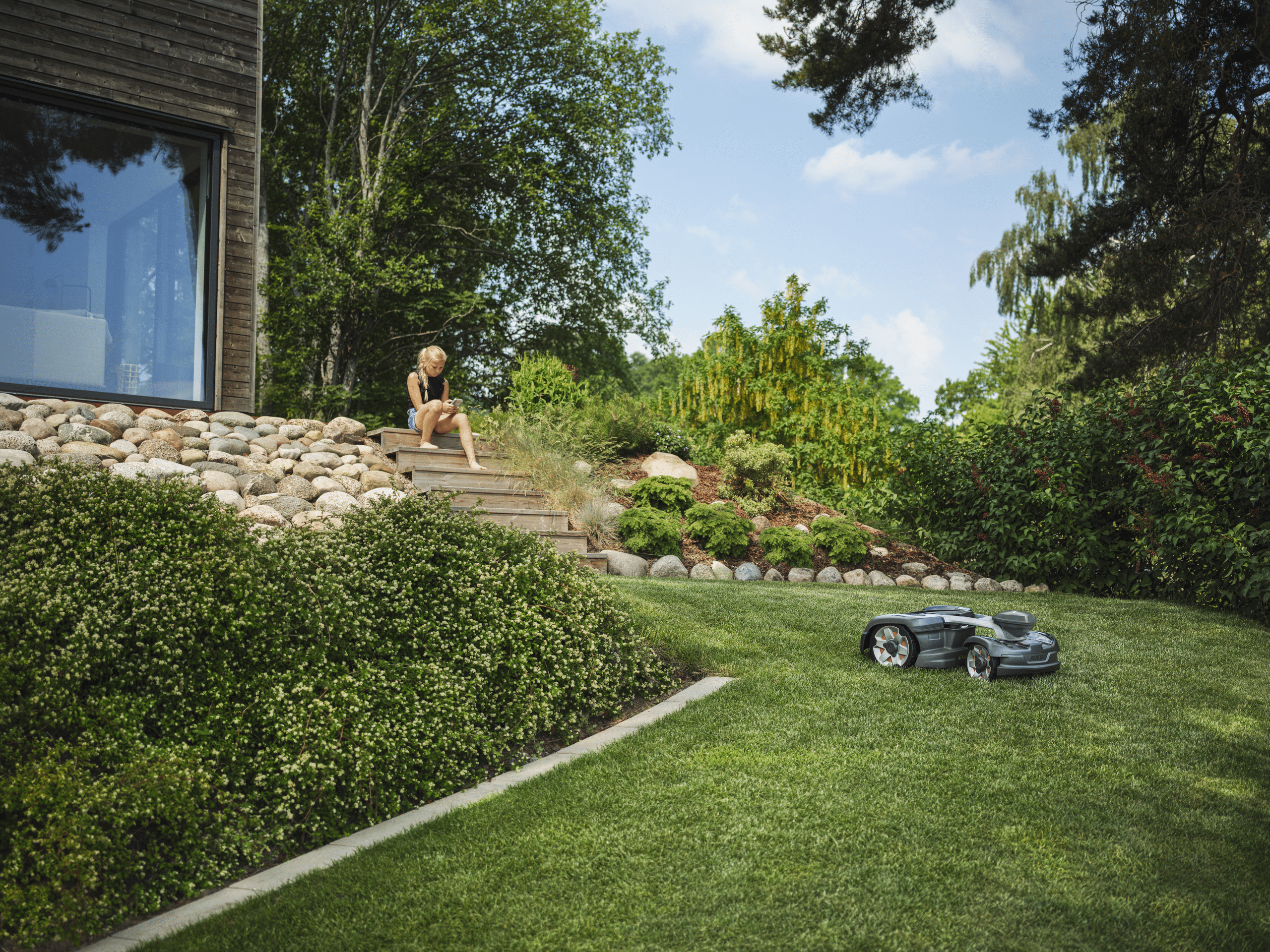 Der Automower 435X AWD NERA von Husqvarna bei Mäharbeiten an einem hanggebauten Grundstück.