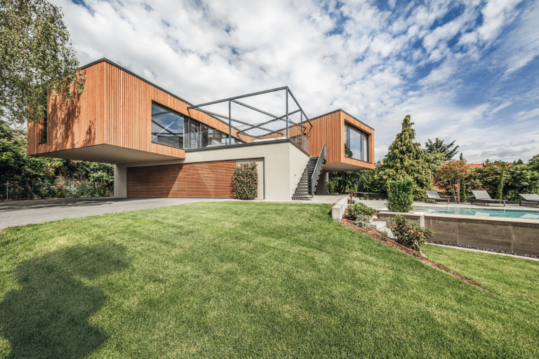 Internorm zeigt ein Architektenhaus mit Holzfassade, Balkon und Treppen zum Garten mit Pool.