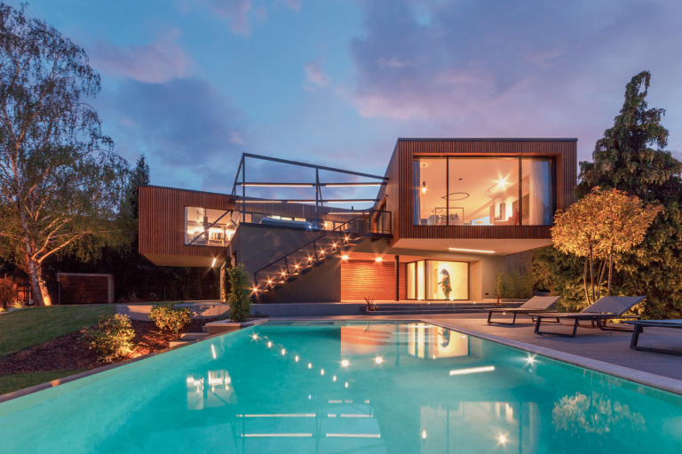 Internorm zeigt ein Architektenhaus mit Holzfassade, großen Fensterfronten und einem Garten mit Terrasse und Pool.