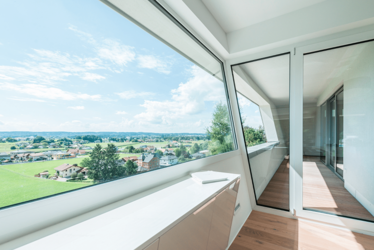 Internorm zeigt eine Terrasse mit übergroßem Glasfenster, einer Glastür und einer Trennwand aus Glas.