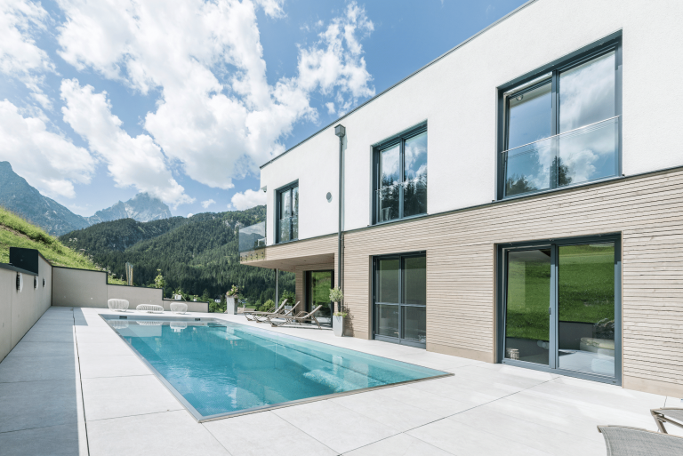 Großflächige Terrasse mit Pool, Glasgeländer-Balkon, großflächigen Bodenfliesen und großen Fensterflächen und Glasschiebetür von Internorm.