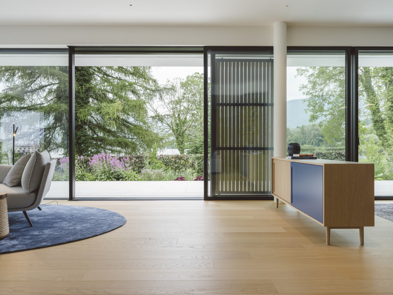 Josko zeigt raumhohe Glasfront mit Glasschiebetür mit schwarzem Rahmen mit Blick auf Terrasse und Garten.