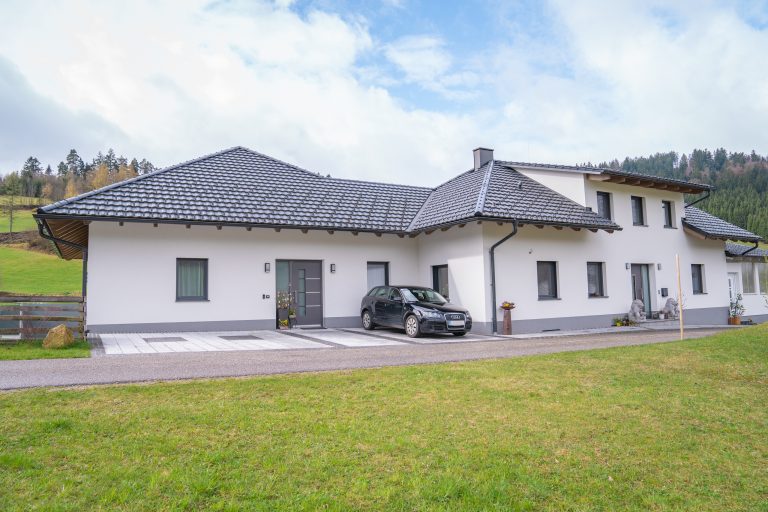 Zweifamilienhaus mit grauem Zeltdach, weisser Fassade, grauen Eingangstüren und Parkplätzen von B. Kern Baugesellschaft.