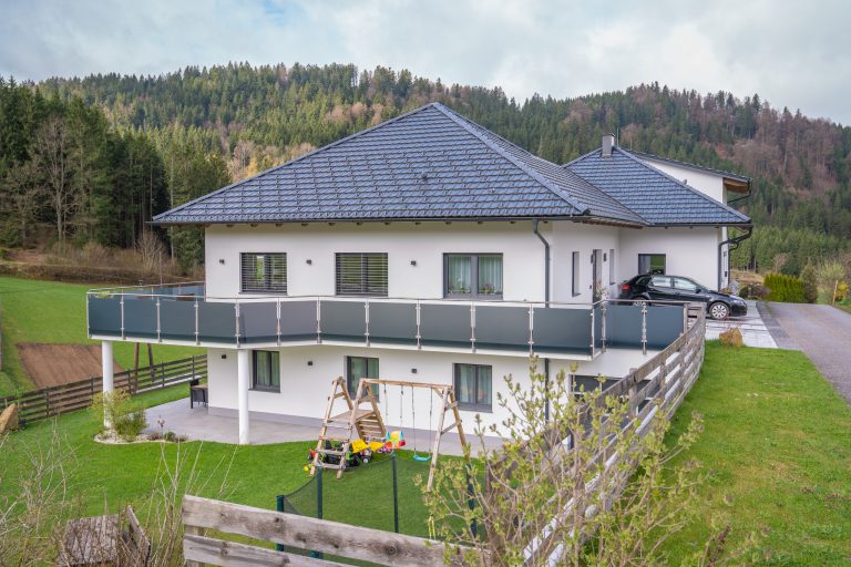 Doppelhaus mit anthrazitfarbenem Satteldach, Balkongeländer aus dunklem Glas und überdachtem Terrassenbereich von B. Kern Baugesellschaft.