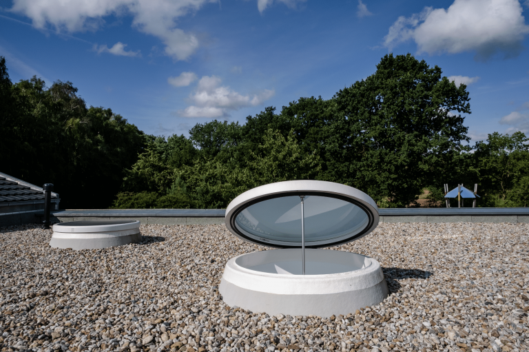 Lamilux zeigt runde Dachfenster auf einer Terrasse mit Kiesboden.