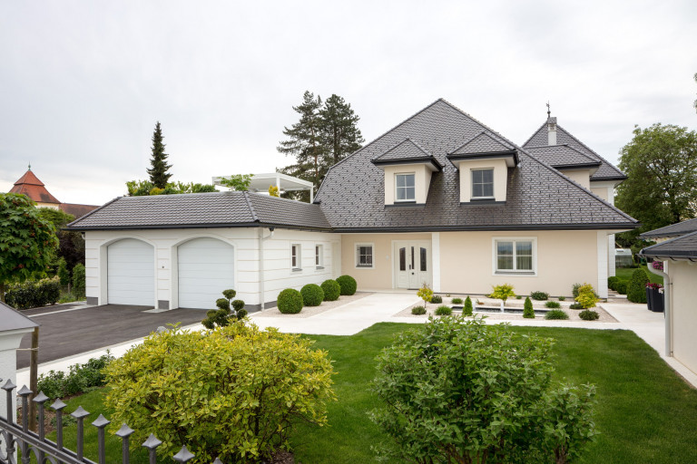 Klassisches Einfamilienhaus in Siedlungslage mit schönem Vorgarten, Doppelgarage, einer wunderschönen Haus-Eingangstür im klassischen Stil mit Stuck, Glas- und Messingelementen sowie passenden Fenstern der Firma Maderböck.