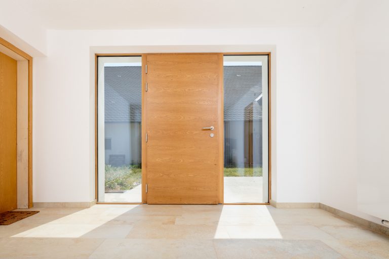 Schlichte und elegante Eingangstüre aus Holz mit durchsichtigen Glasseitenteilen von Maderböck.