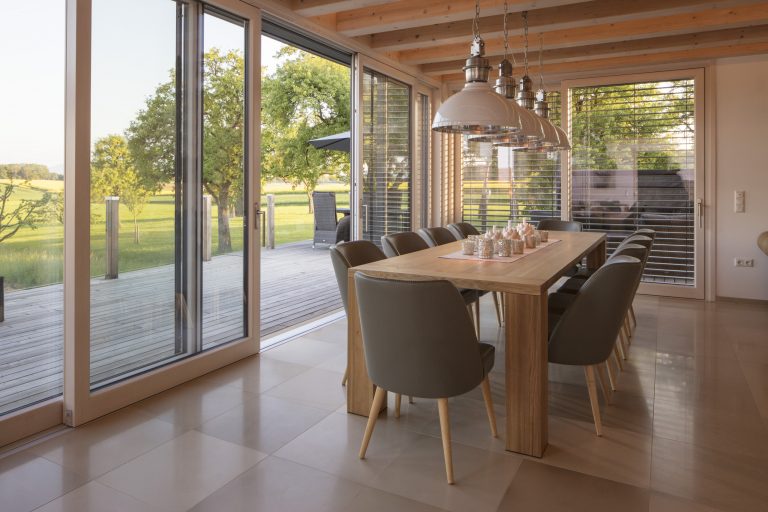 Die barrierefreie und bodentiefe Glasschiebetür von Maderböck führen vom Esszimmer auf die Holzterrasse.