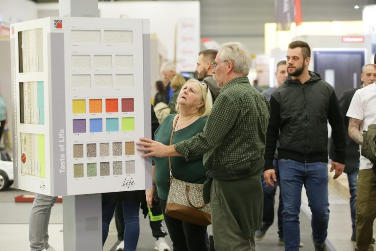 Besucher der Messe Oberwart bei der Begutachtung verschiedener Farbmuster von Hausfassaden.