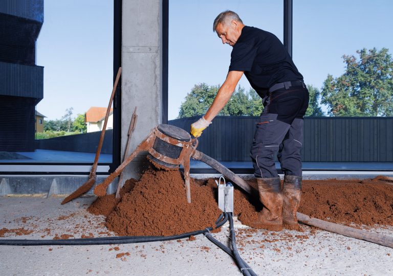 Arbeiter beim Fußbodenaufbau mit thermotec® in einem Raum mit bodentiefen Fenstern.