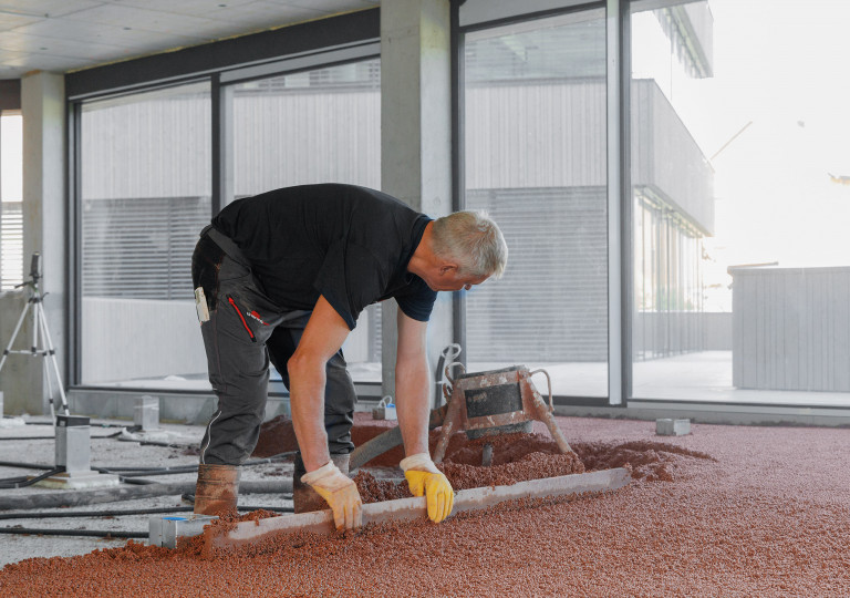 Arbeiter beim Aufbau einer Bodenplatte mit thermotec® in einem Raum mit bodentiefen Fenstern und Ganzglassystem.