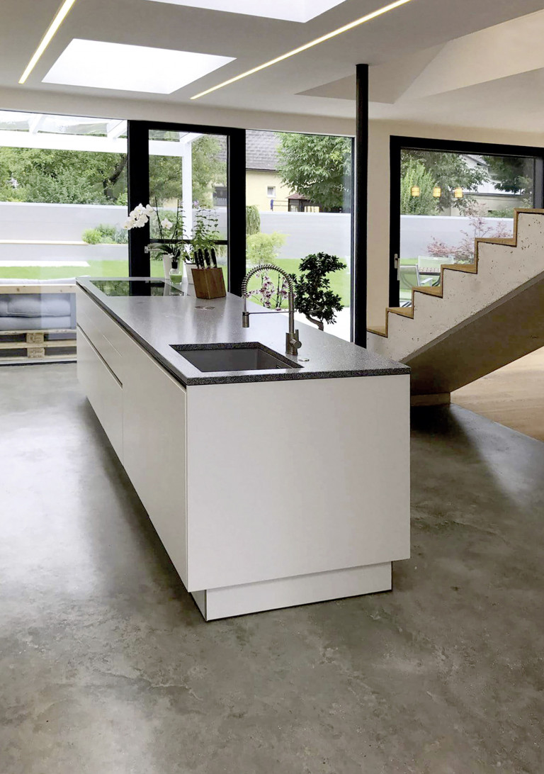 Moderne Inselküche mit freitragender Treppe im Hintergrund auf einer Fußbodendämmung von thermotec®.