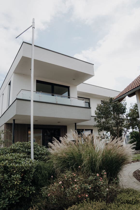 Mehrstöckiges Einfamilienhaus mit Flachdach und Balkon mit Glasgeländer im Musterhauspark Graz.