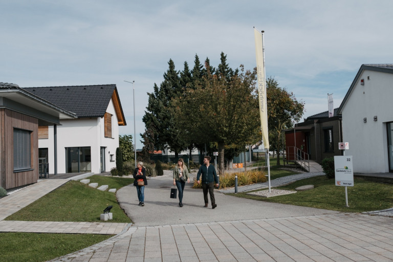 Hausinteressierte Besucher gehen durch die Musterhausstrasse im Musterhauspark Haid.