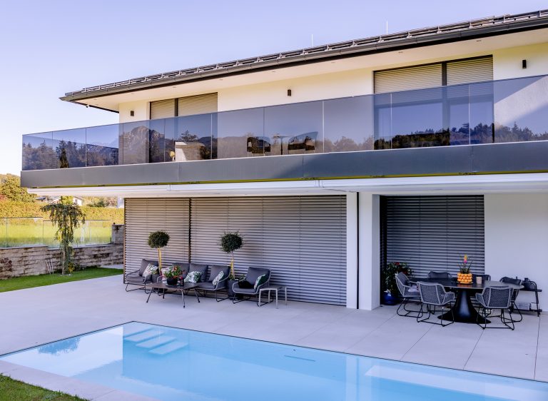 Modernes Einfamilienhaus mit Balkon und Glasgeländer, Pool, Terrasse und geschlossene Jalousie von Newo.