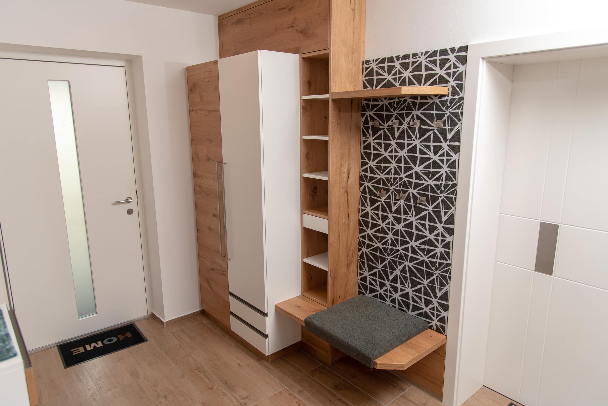 Garderobe mit Kasten, gepolsterter Sitzgelegenheit und offenem Regal in Weiß und Holz von Pröll Wohnideen.