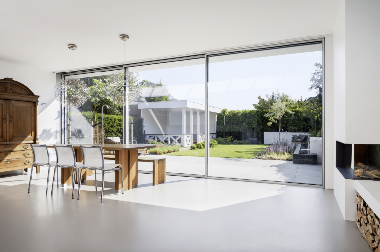 Essbereich mit Kamin und geöffneten Glas-Schiebeelementen von Solarlux zum Garten.