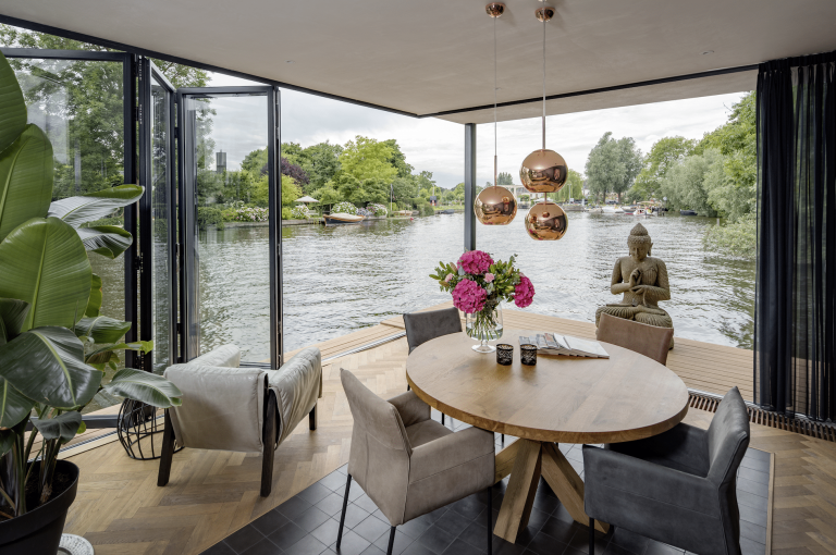 Gemütlicher Sitzbereich mit geöffneter Glas-Faltwand von Solarlux und Blick auf den Fluss.