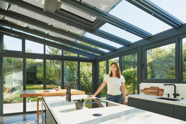 Solarlux zeigt modernen Küche im Wintergarten mit Glasfaltwänden mit Blick auf die Terrasse.