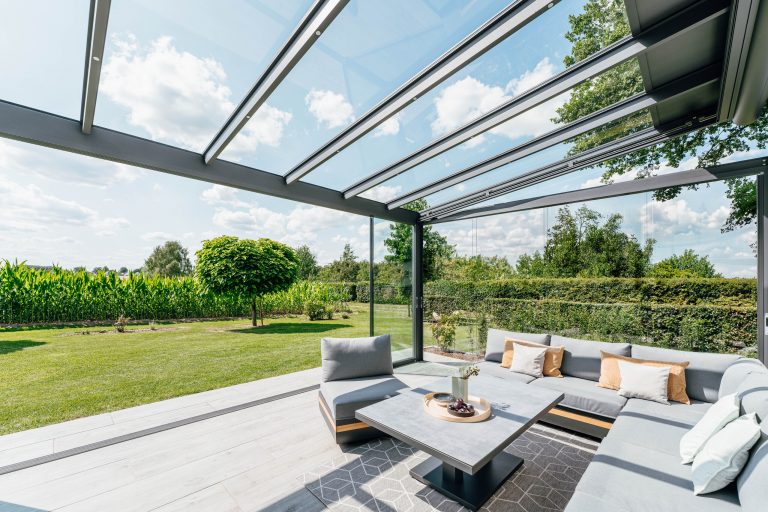 Grosser Wintergarten mit Glasdach, Glasseitenwänden und Glasfaltwänden von Solarlux der barrierefrei in den Garten führt.