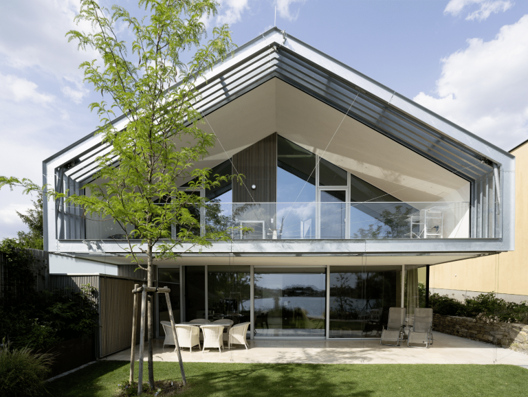 Modernes Einfamilienhaus mit Satteldach, bodentiefen Fenstern und Fixverglasung und Balkon von Weissenseer Holz-System-Bau.