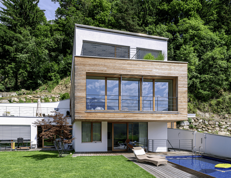 Einfamilienhaus mit Holzfassade, Flachdach, Terrasse, Garten, Balkon und Pool von Weissenseer Holz-System-Bau.