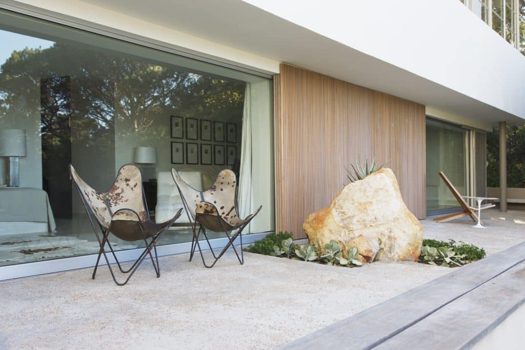 Haus mit Bodenplatte und großer Terrasse mit gemütlichen Sitzmöbeln.